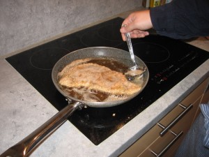 Das Schnitzel wird beim braten mit Fett begossen